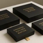 Set of luxury black drawer-style packaging boxes with gold foil text showcasing premium print finishes on a light surface.