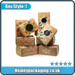 Stack of kraft Christmas treat boxes with festive snowflake and wreath patterns, each with a display window.