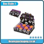 Halloween-themed cupcake display box with skeleton and pumpkin graphics, holding colourful cupcakes in purple and orange icing