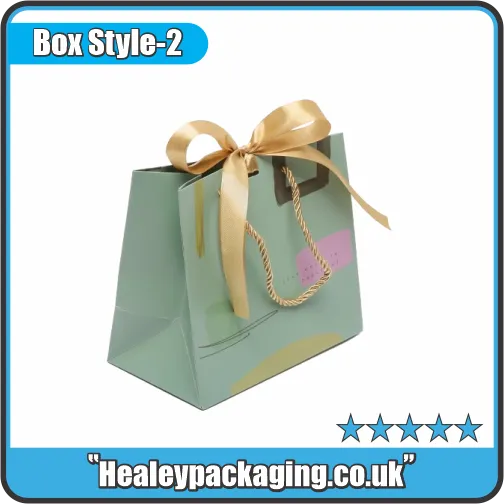 Glossy pastel green gift bag with gold ribbon bow and twisted rope handles.