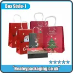 Assorted Christmas gift bags featuring festive prints, including Santa, reindeer, snowman, and Christmas tree designs with white twist handles.