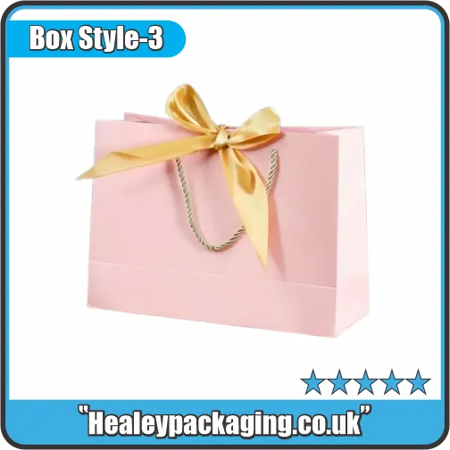 Light pink gift bag featuring a gold satin bow and braided rope handles.