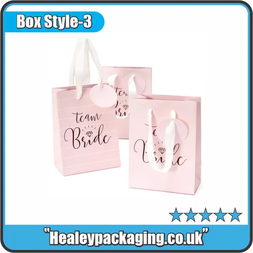 Light pink “Team Bride” goody bags with white ribbon handles and matching round tags.