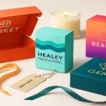 Colourful custom packaging boxes including beauty, market, gem, and Healey Packaging designs displayed with ribbons and candle on a clean studio background.