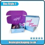Printed subscription-style mailer box with hinged lid, open to display assorted branded items inside