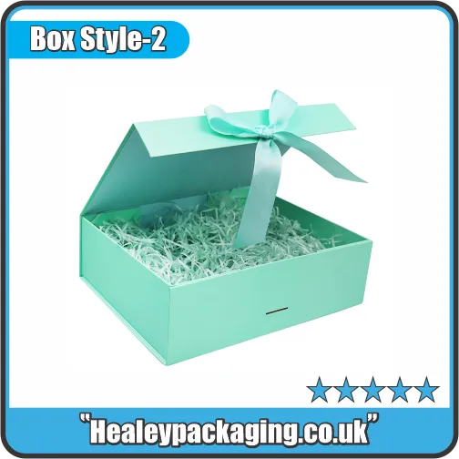 Rigid gift box with lift-off lid, shown open with decorative ribbon and shredded paper filling.