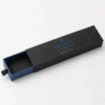 Black and blue custom pen box with sliding drawer, ribbon pull and printed branding.